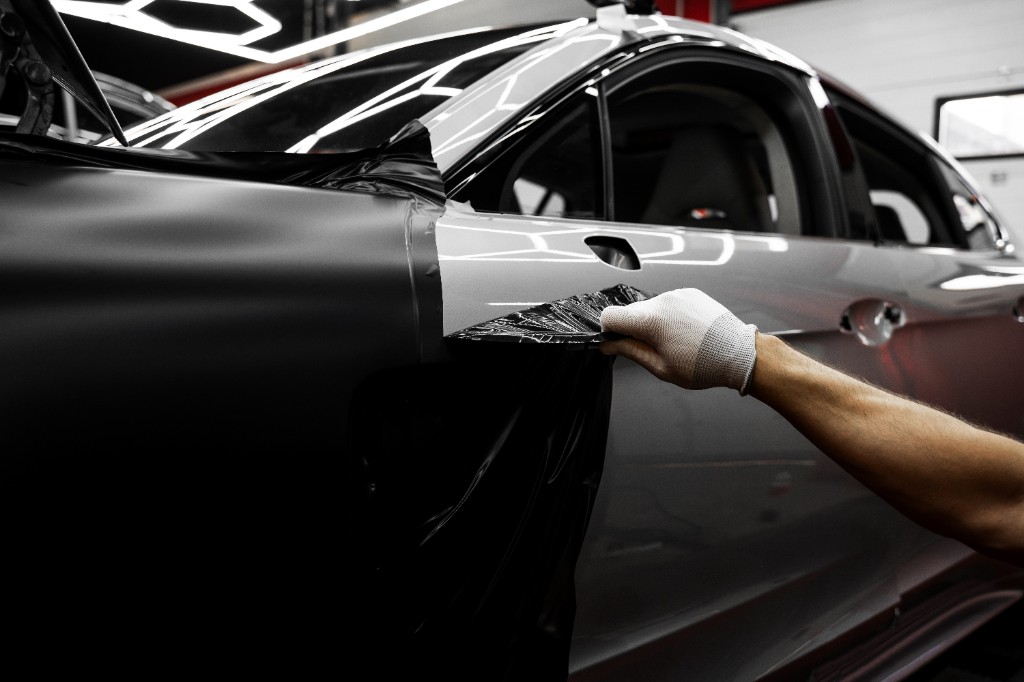 Technician applying black vinyl wrap to a vehicle